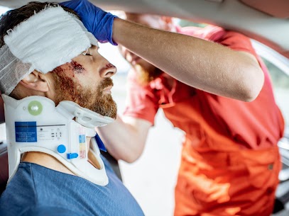 Medic applying bandage on the head of victim with serious damages sitting on the driver seat after the road accident. Providing emergency medical assistance